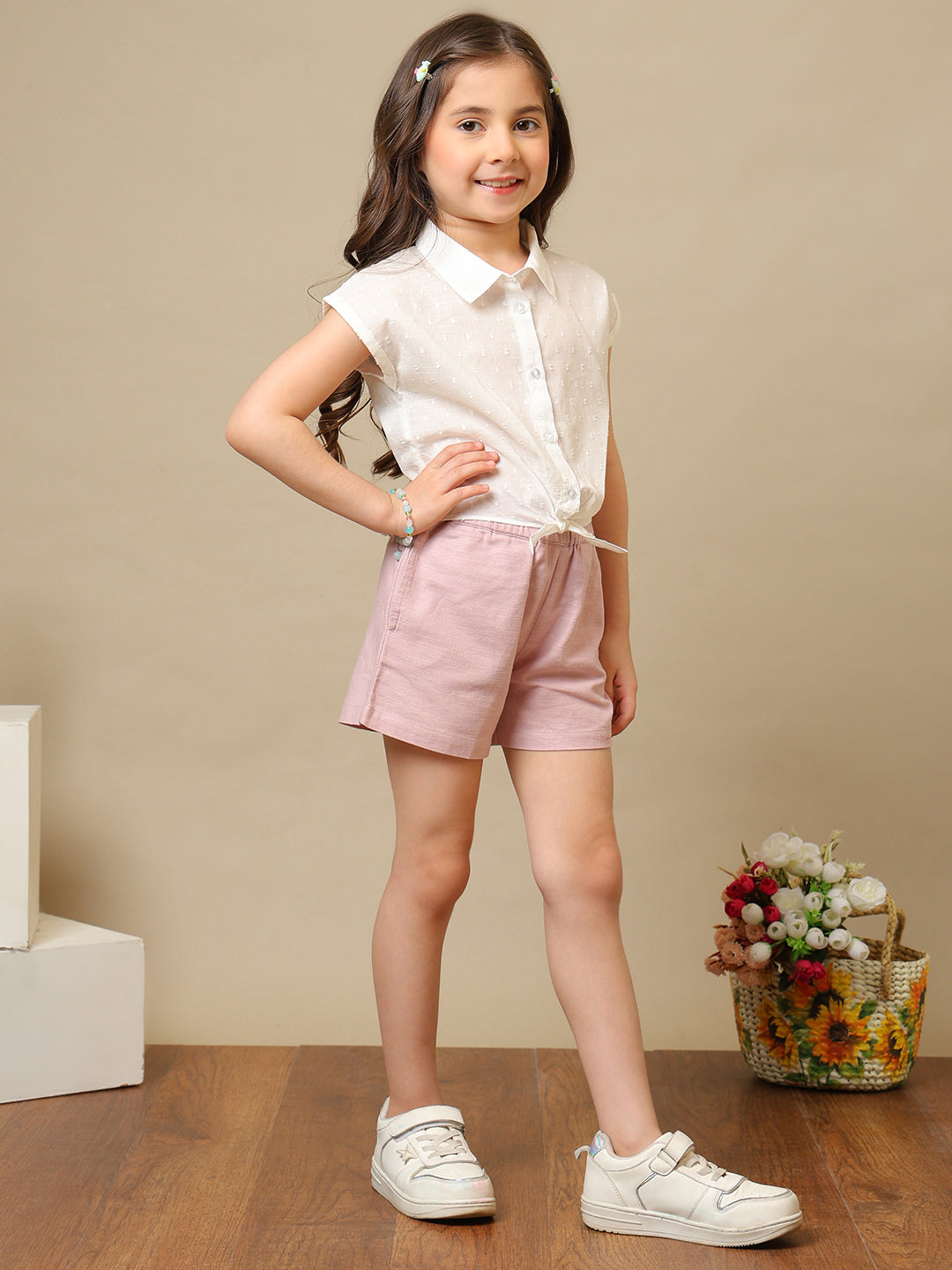 White girls sleeveless top with ruffle detailing and pink shorts co-ord set