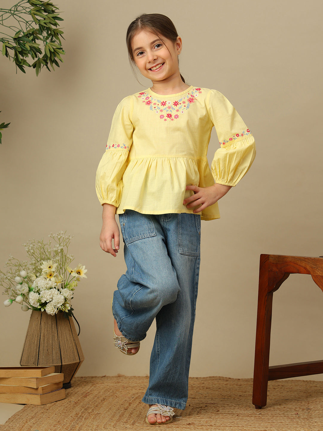 Girls yellow cotton peplum top with multicolour floral embroidery, round neckline and three-quarter balloon sleeves.